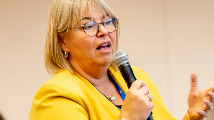Woman asking question and holding microphone.