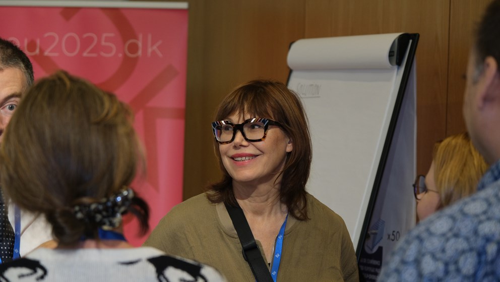 Woman smiling and standing in front of whiteboard